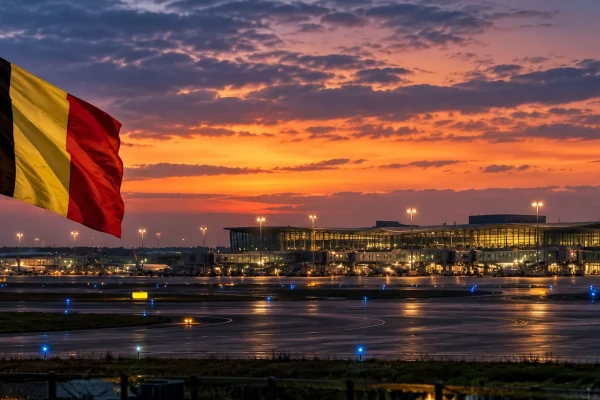 Belgian flag overlooking an airport runway and terminal at dusk