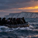 AI-generated editorial illustration of an overcrowded small boat crossing rough Channel waters towards the Kent coast.