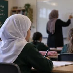 Illustration of a young primary-school pupil wearing a white hijab in a classroom.