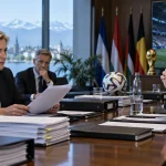 Illustration of football administrators reviewing documents in a FIFA-style boardroom with a World Cup stadium visible on a screen.