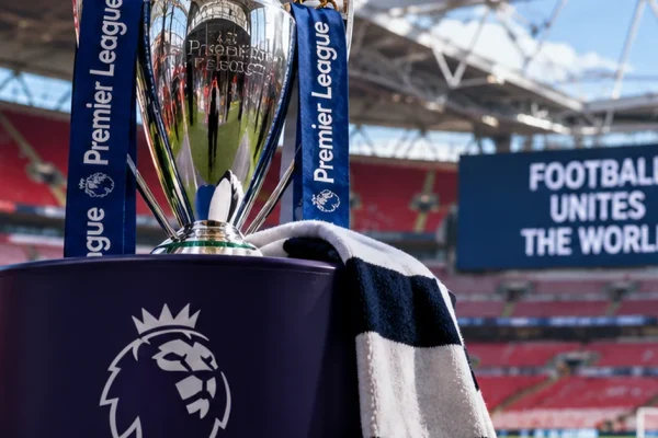 Premier League trophy inside an empty football stadium, illustrating the extended international break.