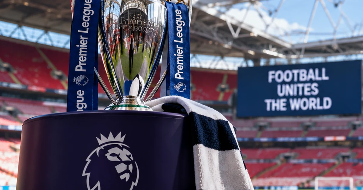 Premier League trophy inside an empty football stadium, illustrating the extended international break.