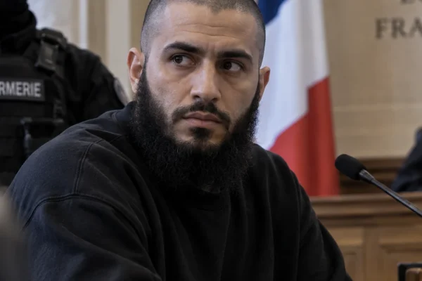 Defendant seated in a French courtroom under guard, illustrating the Paris trial of former Islamic State member Othman Garrido.