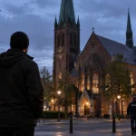 Illustration of a man observing a church in a German city while police officers patrol nearby.