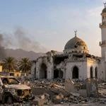 Damaged mosque and vehicle amid rubble following a projectile strike