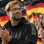 Illustration of Jürgen Klopp in a football stadium surrounded by supporters waving German flags.