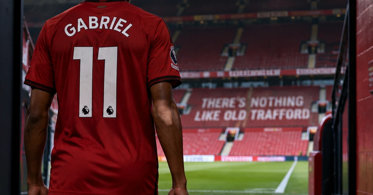 A young footballer in red walking towards the pitch from a stadium tunnel, illustrating JJ Gabriel's request to leave Manchester United.
