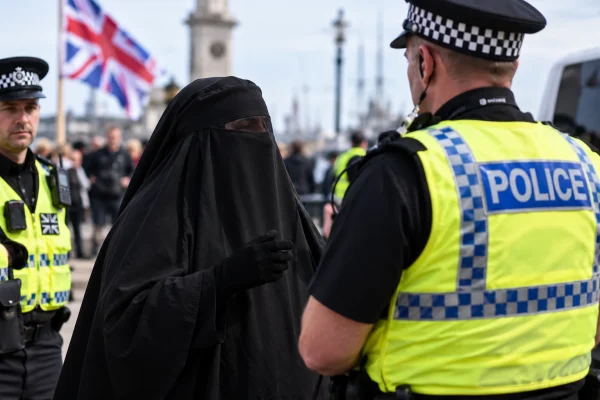 Face-covered protester speaking with police at a British demonstration