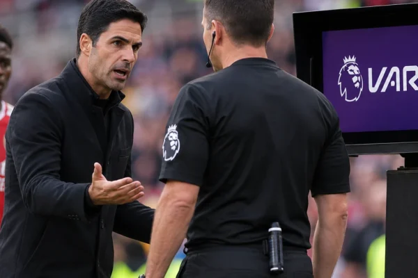 Football manager confronting a Premier League referee beside a VAR monitor