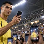 Illustration of a Ronaldo-like football star using a smartphone in a packed stadium as supporters hold up their phones.