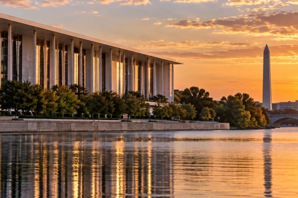 The Kennedy Center beside the Potomac River in Washington DC at sunset, illustrating the dispute over its renovation and naming.