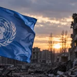 Editorial illustration of a United Nations flag beside war-damaged buildings representing the UN investigation into conflict-related sexual violence in Ukraine.
